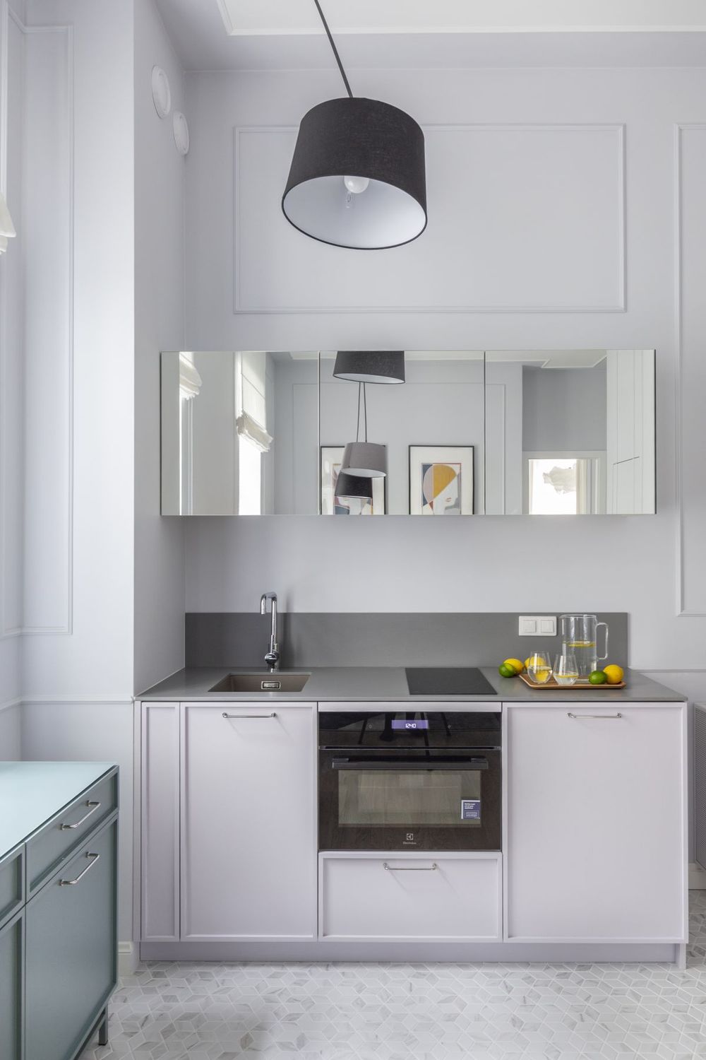 Phòng bếp và khu vực ăn uống bố trí đối diện phòng khách với sàn ốp gạch sáng màu, 'tone sur tone' với tủ bếp và màu tường. Đặc biệt, hệ thống tủ bếp trên với cửa ốp gương giúp tạo chiều sâu và 'nhân rộng' không gian nhỏ.