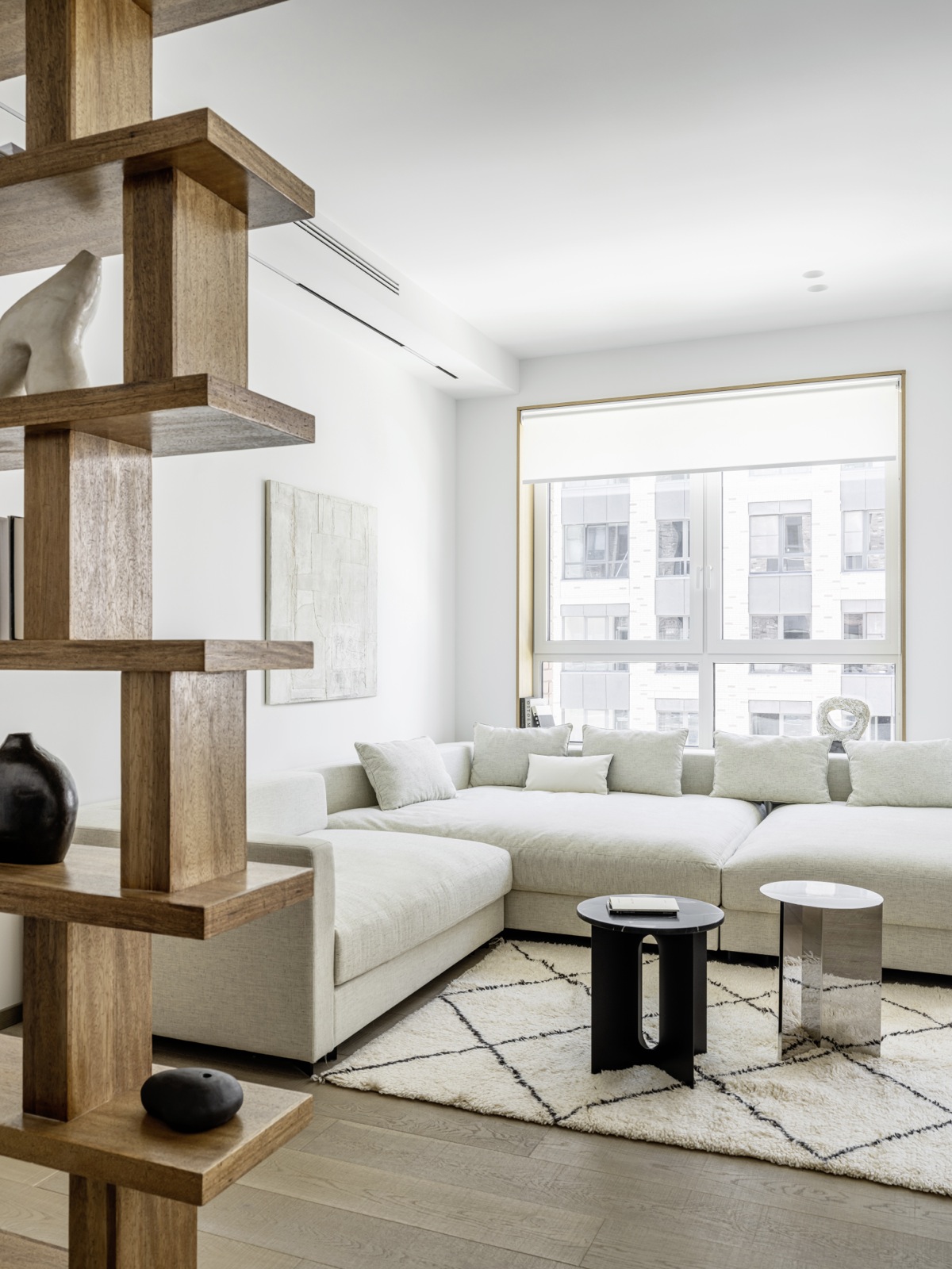 Phòng khách bố trí ghế sofa góc với màu trắng ấm, 'tone sur tone' với tường và trần nhà giúp xóa bỏ ranh giới của căn hộ một cách trực quan.