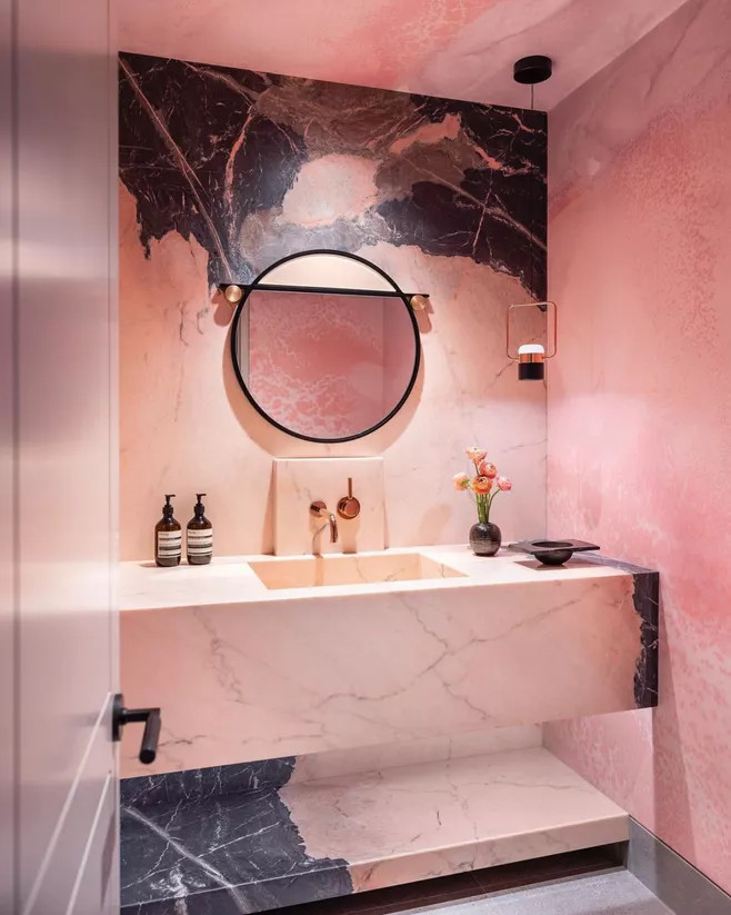 Phòng tắm kết hợp của vật liệu đá cẩm thạch 2 tone màu đen bí ẩn và hồng nữ tính với những đường vân trắng - xám. Từ bức tường đến bồn rửa và kệ phía dưới càng tăng thêm sự đắt giá cho không gian thư giãn.