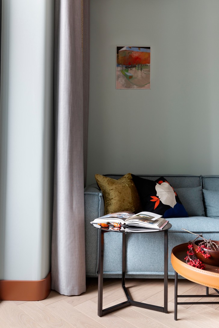 Vì căn hộ thiết kế kiểu studio nên phòng khách, bếp, khu vực ăn uống và phòng ngủ được thiết kế trên một mặt phẳng để tạo cảm giác thông thoáng. Phòng khách với ghế sofa màu xanh lam nhạt, bàn nước đôi hình tròn cho vẻ đẹp duyên dáng.