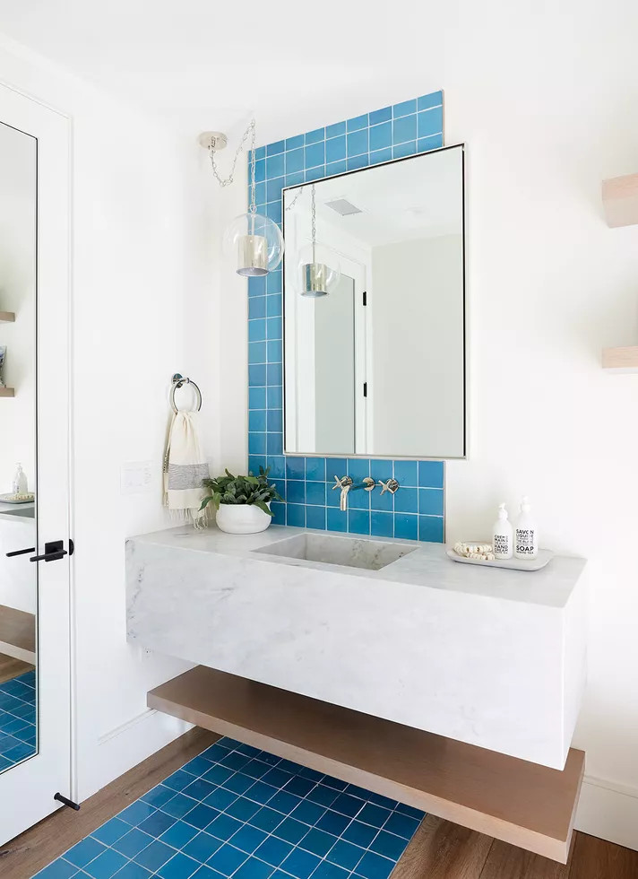 Nếu bạn đã từng nghe qua khái niệm 'backsplash' trong phòng bếp thì khi ngắm nhìn bức hình này, những viên gạch mosaic màu xanh lam nhạt kéo dài từ tường đến sàn nhà trông cũng như 'backsplash' của phòng tắm đúng không nào?