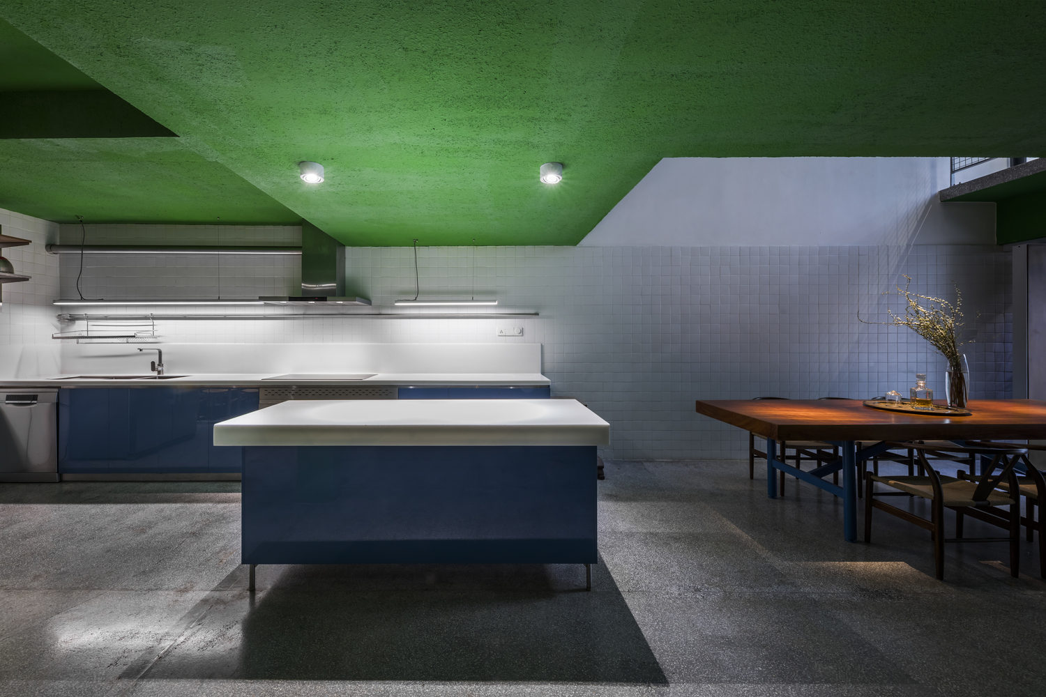 Không gian phòng bếp và đảo bếp sử dụng gam màu màu xanh lam đậm kết hợp với sắc trắng để tôn lên vẻ nổi bật của trần sơn màu xanh lá.