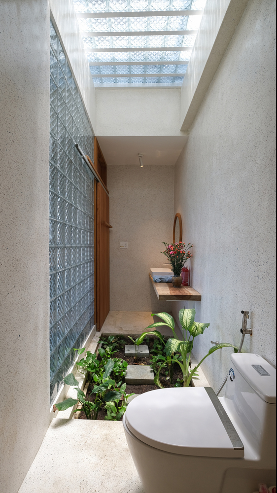 Khu vực nhà vệ sinh và bồn rửa được bao bọc bởi hệ thống gạch kính lấy sáng ở cả trần và tường. Chính giữa còn có cả khu vực trồng cây xanh mướt.