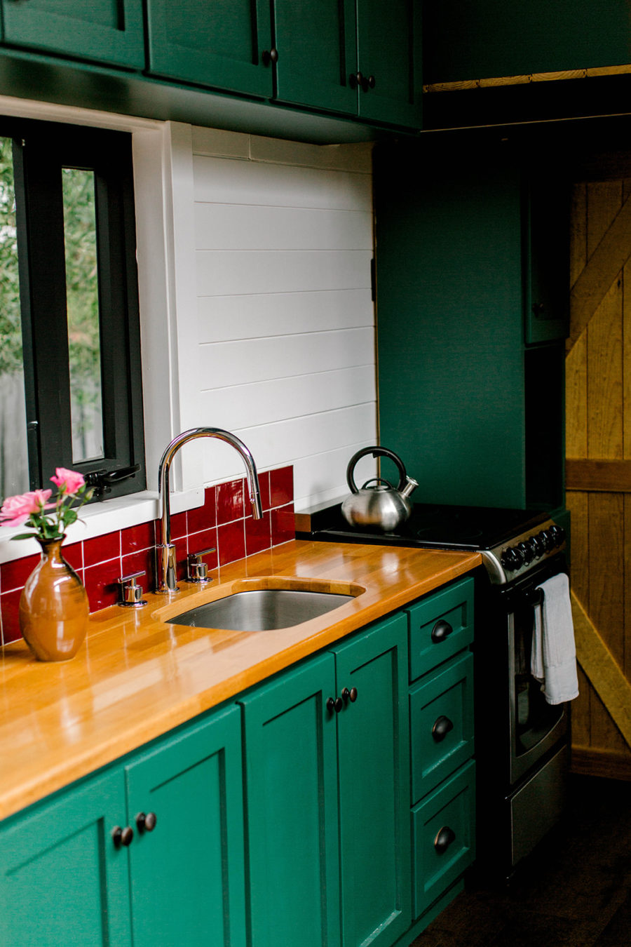 Phòng bếp và khu vực ăn uống sử dụng gam màu xanh ngọc lục bảo kết hợp với những viên gạch mosaic màu đỏ sáng bóng tạo nên vẻ đẹp nổi bật, cuốn hút.