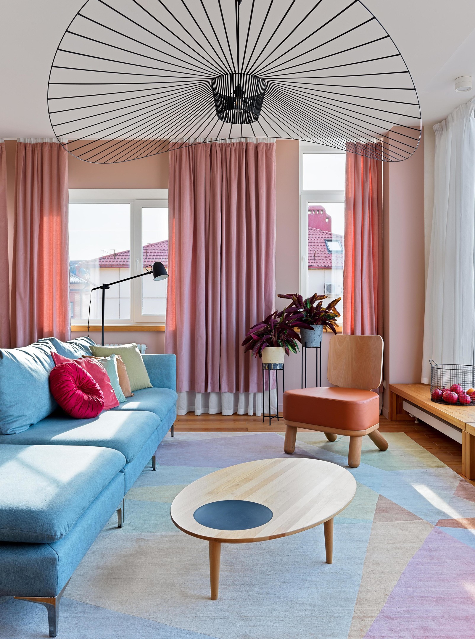 Phòng khách xinh đẹp với bộ ghế sofa màu xanh lam nhạt kết hợp với thảm trải sàn và những chiếc gối tựa nhiều màu sắc. Phía cửa sổ, rèm che sắc hồng ngọt ngào hòa quyện cùng màu nắng ấm áp vô cùng.