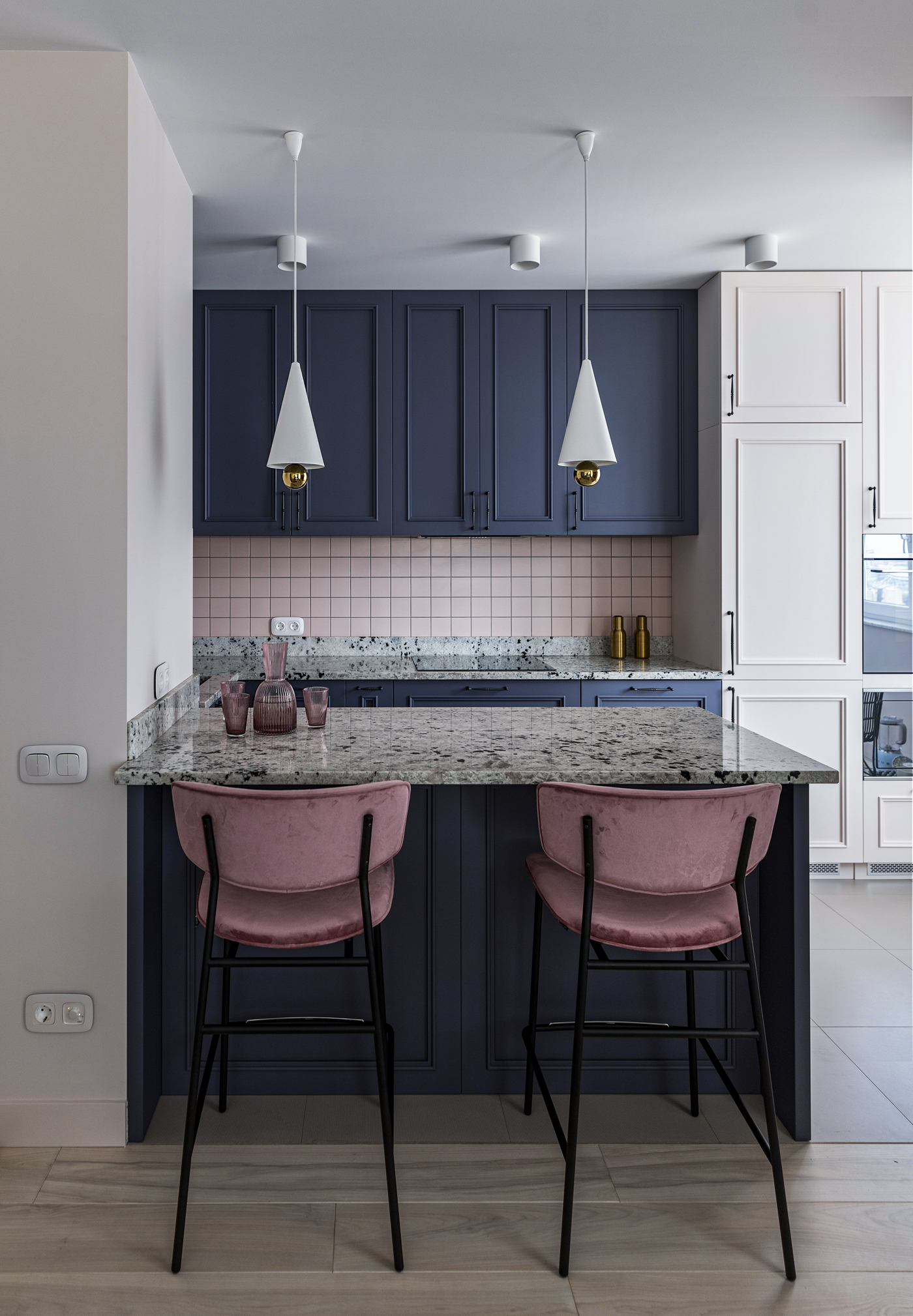 Mặc dù sở hữu diện tích rất nhỏ nhưng phòng bếp này vẫn gây ấn tượng với người nhìn bởi cách kết hợp sơn tủ màu xanh lam đậm, riêng khu vực backsplash ốp gạch mosaic hồng nhạt cùng cặp ghế 'tone sur tone'.