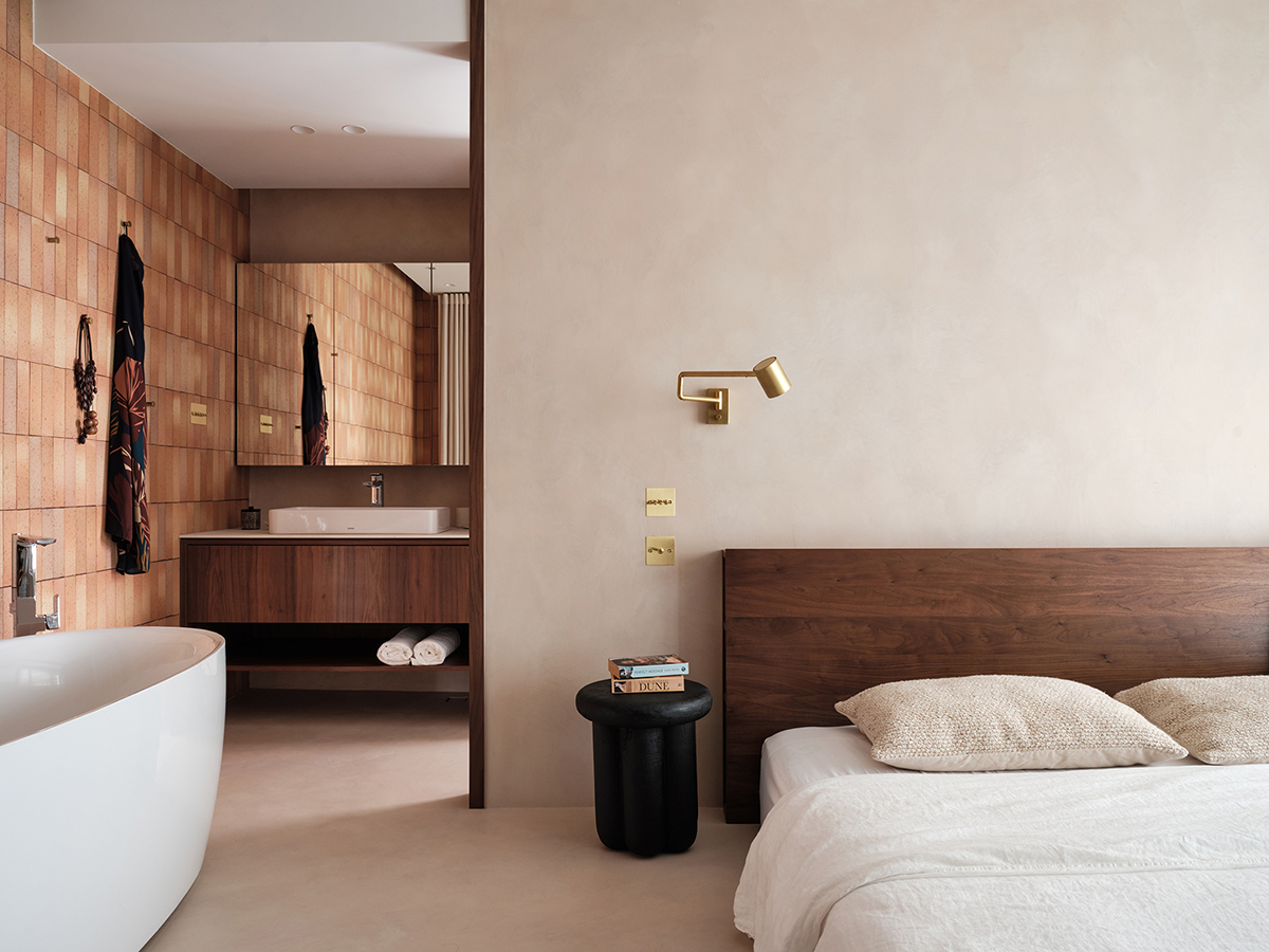 Không gian phòng tắm được bố trí ngay trong phòng ngủ của cặp đôi, với bồn tắm nằm thoải mái, tường ốp gạch thô mộc cho cái nhìn ấm áp.