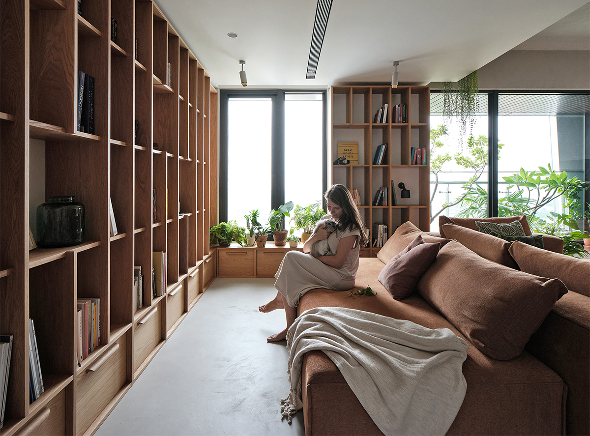 Không gian phía sau sofa phòng khách được sử dụng như một thư viện nhỏ và góc thư giãn, đọc sách,... với ghế ngồi êm ái cùng hệ thống tủ lưu trữ cao kịch trần.