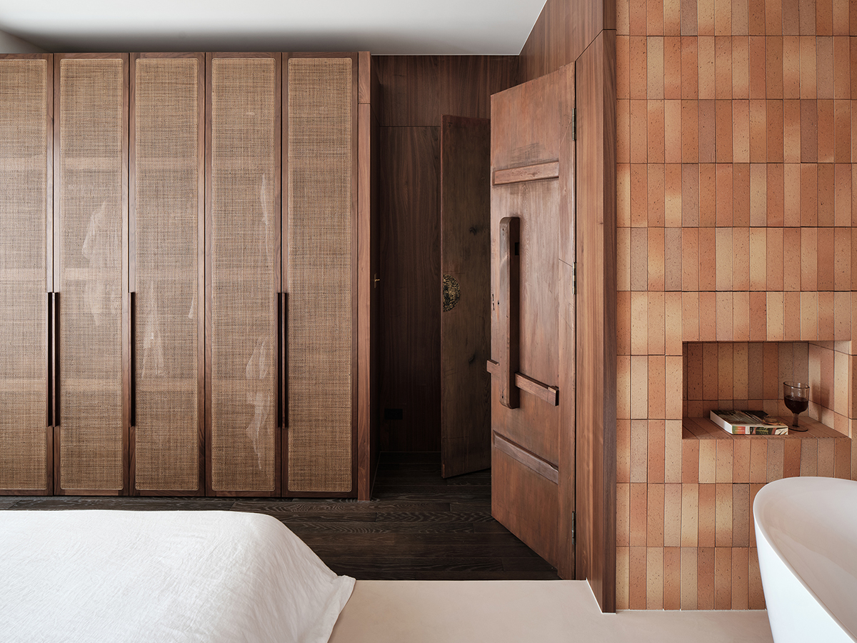Đối diện giường ngủ là hệ thống tủ quần áo có chiều cao kịch trần, khung gỗ kết hợp những cánh cửa làm bằng mây tre đan đậm chất Á Đông.
