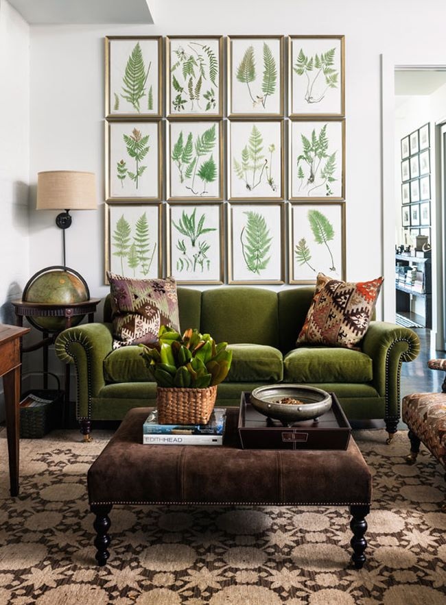 Chiếc ghế sofa phong cách cổ điển với gam màu xanh ô liu và chất vải bọc nhung êm ái. Phía sau nó là bộ tranh treo tường chủ đề hoa lá, một ý tưởng trang trí phòng khách rất hài hòa đúng không nào?