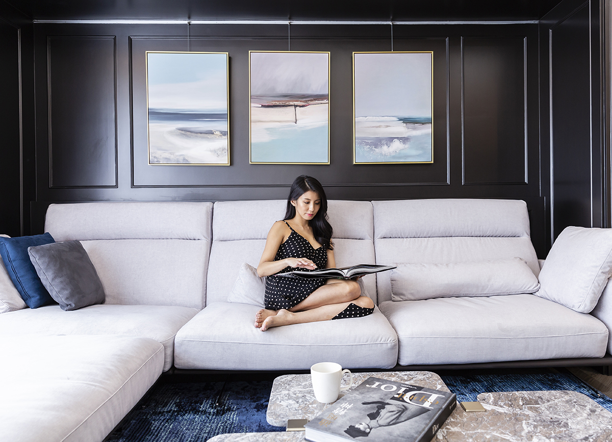 Phòng khách bố trí sofa màu trắng êm ái, nổi bật trên bức tường sơn màu đen tuyền cùng bộ tranh treo chủ đề biển xanh, tuy đơn giản mà rất sang trọng.