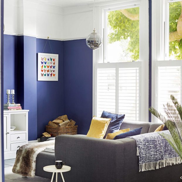 Cách chọn màu sơn tường thông minh có thể 'kéo cao' trần phòng khách. Ở đây, chủ nhân đã sơn một nửa bức tường phía dưới màu xanh lam đậm, nửa trên màu trắng và kéo qua ô cửa sổ, trần nhà, giúp không gian nhỏ thoáng sáng hơn.
