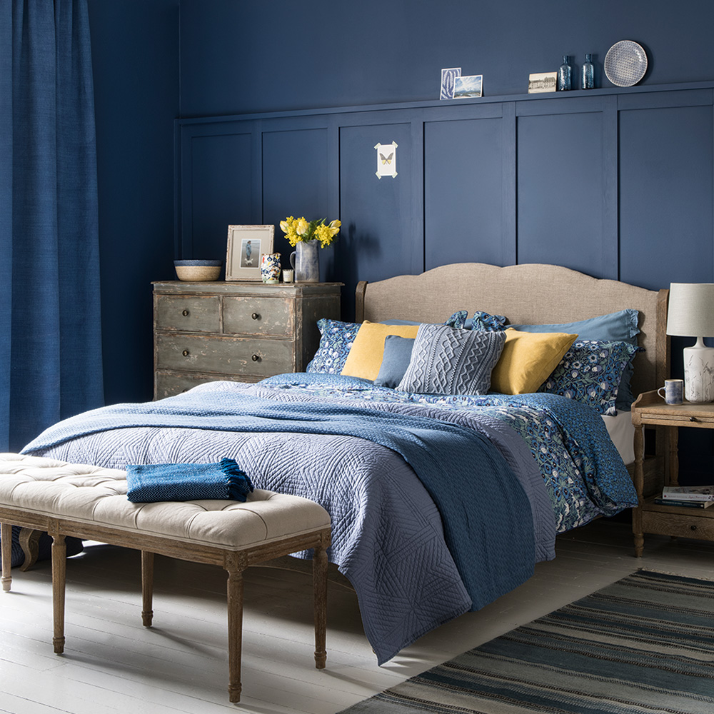 Phòng ngủ vintage với nội thất gỗ in đậm dấu ấn thời gian, kết hợp sự tươi sáng của tường màu xanh lam chăn gối, rèm che,... cho không gian vừa mới mẻ vừa hoài cổ.