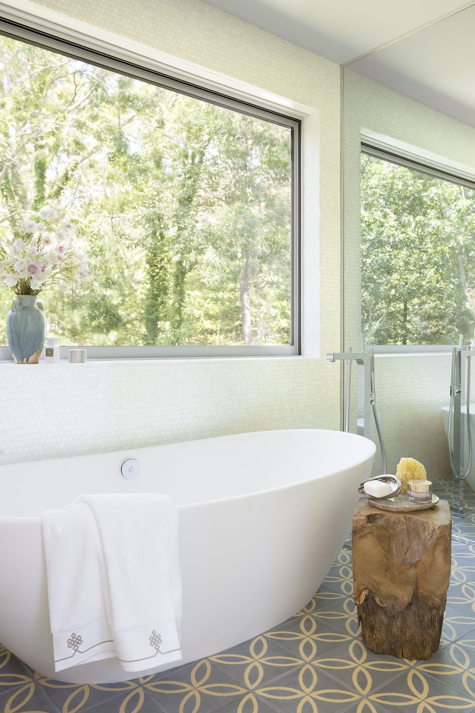 NTK nội thất đã khéo léo sử dụng cửa kính kết hợp gương soi để nhân rộng không gian và ánh sáng trong phòng tắm tuyệt đẹp này. Màu xanh của cây cối kết hợp với chiếc bàn gỗ, gạch bông lát sàn cổ điển trông rất mộc mạc.