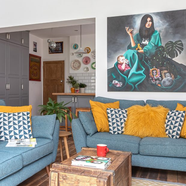 Phòng khách sử dụng cặp ghế sofa màu xanh lam bố trí vuông góc để phân vùng với phòng bếp và khu vực ăn uống.