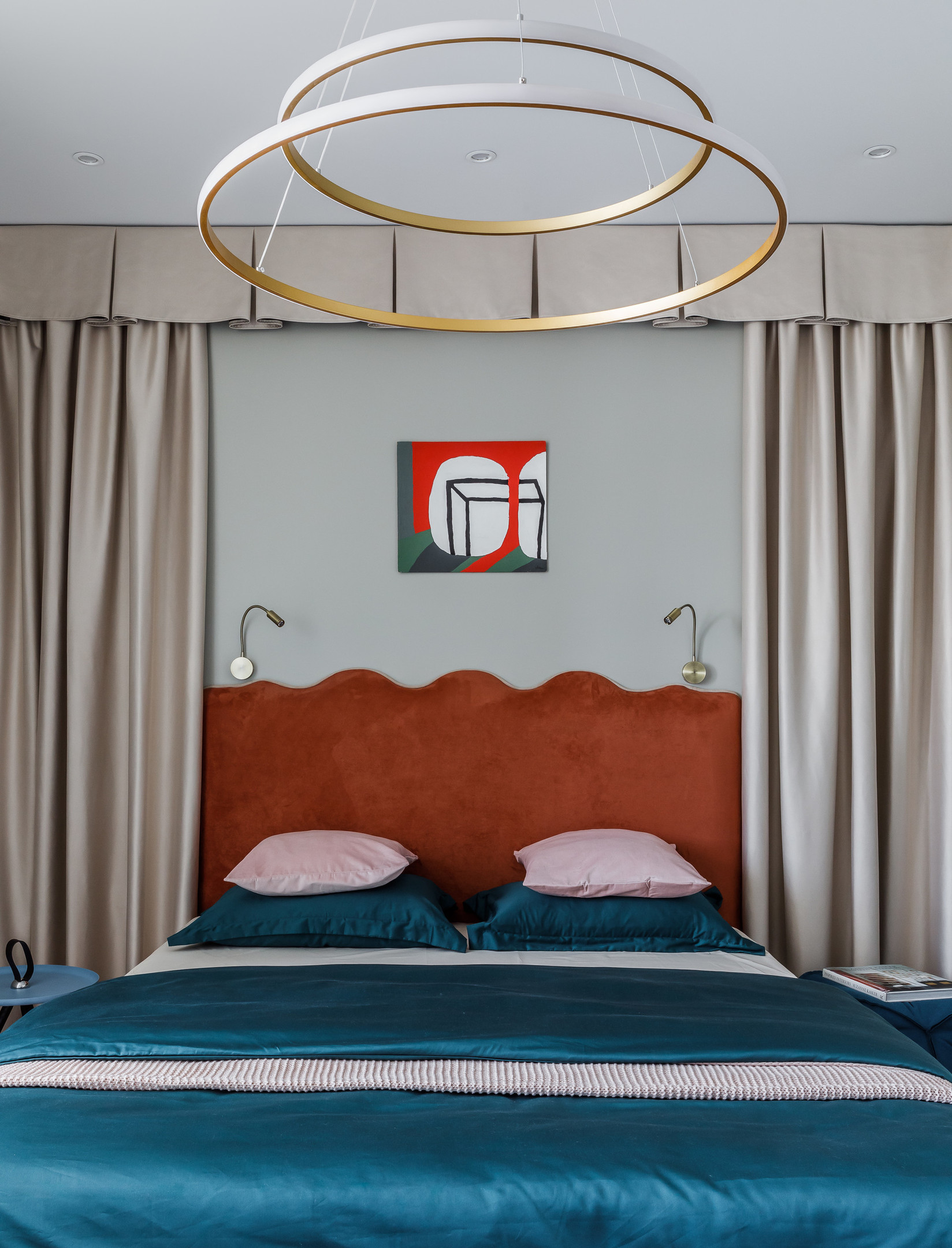 Phòng ngủ bừng sáng không chỉ ở đầu giường màu cam gạch, chăn ga gối sắc xanh coban mà còn ở chiếc đèn trần được tạo nên từ 2 vòng tròn lớn bé khác nhau.