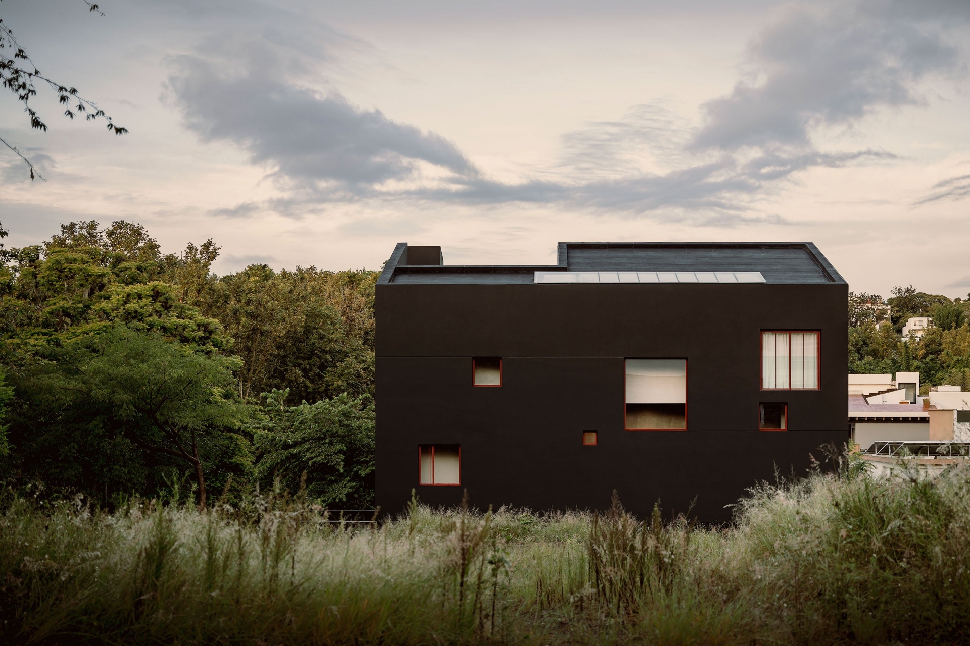 Ngôi nhà với mặt tiền màu đen bí ẩn, các cửa sổ với độ cao và kích thước khác nhau , nổi bật những những ngọn cây xanh rì cao vút. 