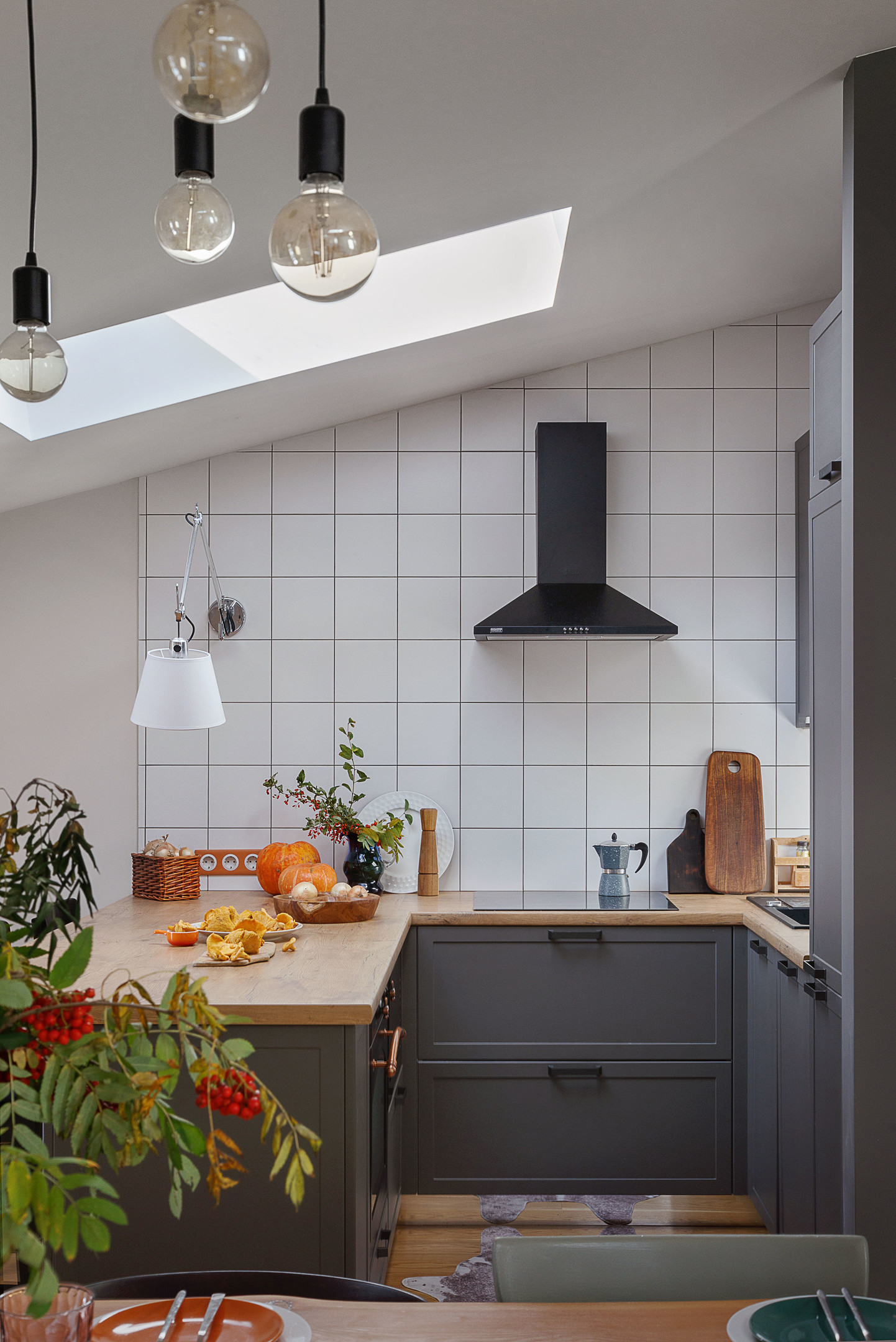 Phòng bếp nhỏ nhưng sở hữu cửa sổ mái cung cấp ánh sáng thoáng đãng cho không gian nấu nướng. Sự kết hợp giữa gạch thẻ vuông trắng và màu sơn tủ bếp xám đậm cho cái nhìn vừa cổ điển vừa hiện đại.