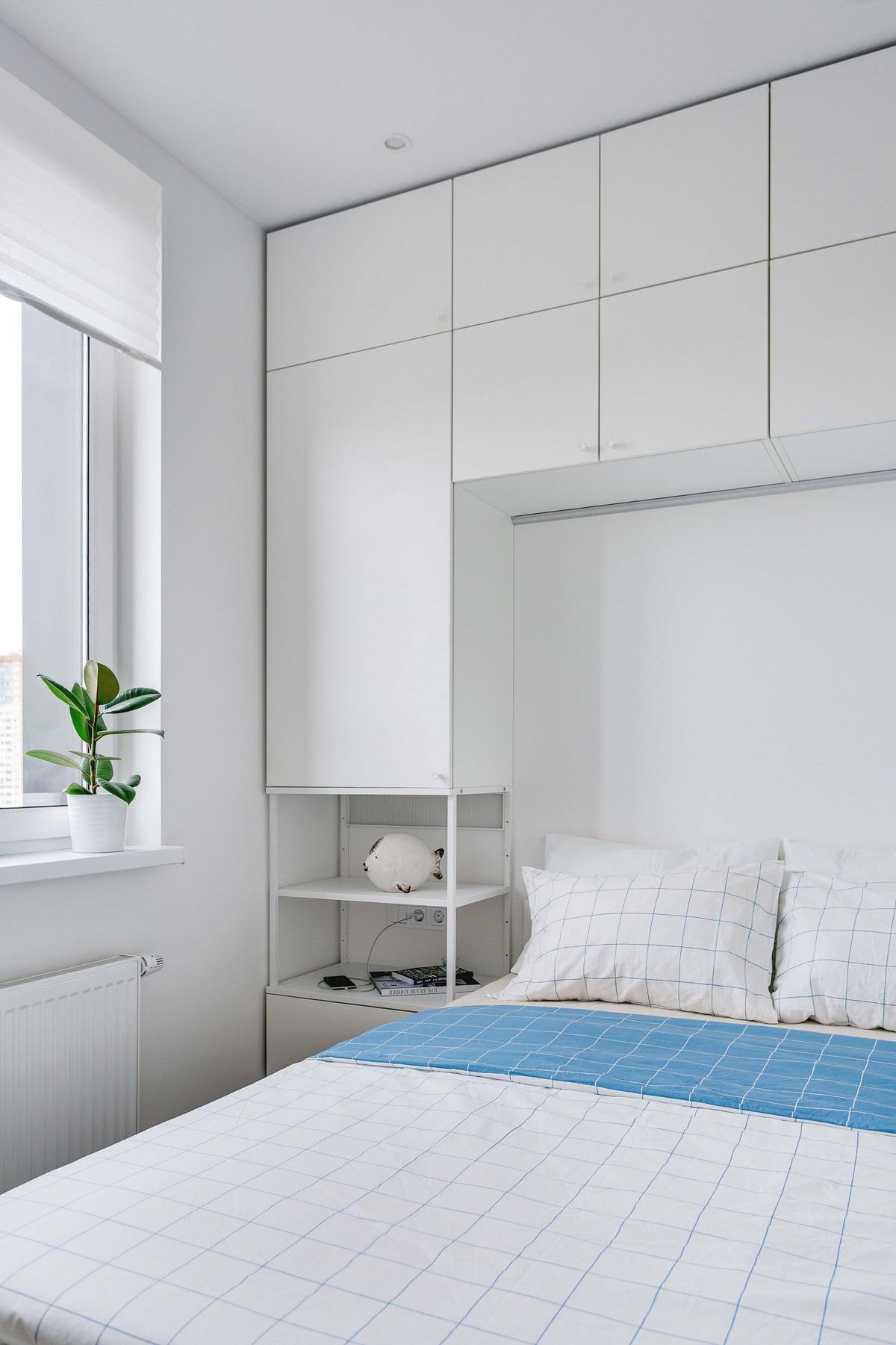 Và đây là phòng ngủ nhỏ xinh với gam màu trắng chủ đạo kết hợp một chút sắc xanh lam tươi tắn. Hệ thống tủ kệ cao kịch trần giúp tối ưu hóa không gian lưu trữ.