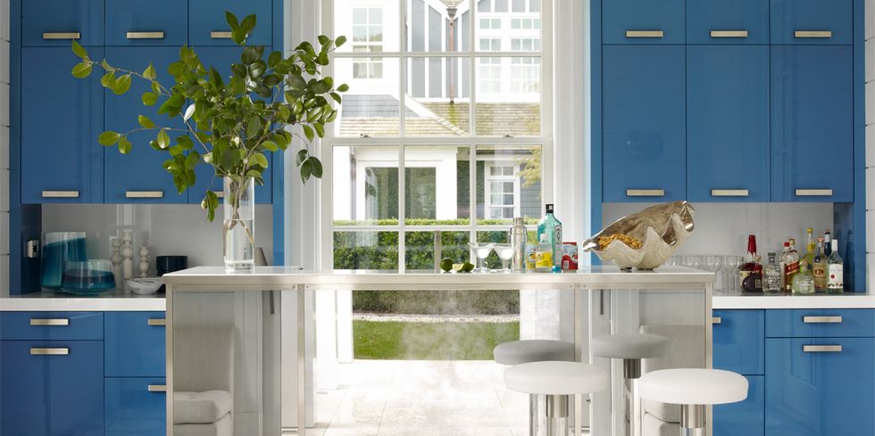 Hệ thống tủ bếp trên và dưới được sơn màu xanh lam với bề mặt hoàn thiện sáng bóng, kết hợp đảo bếp ốp gương càng tăng thêm phần tươi sáng và bắt mắt cho không gian nấu nướng trong nhà.