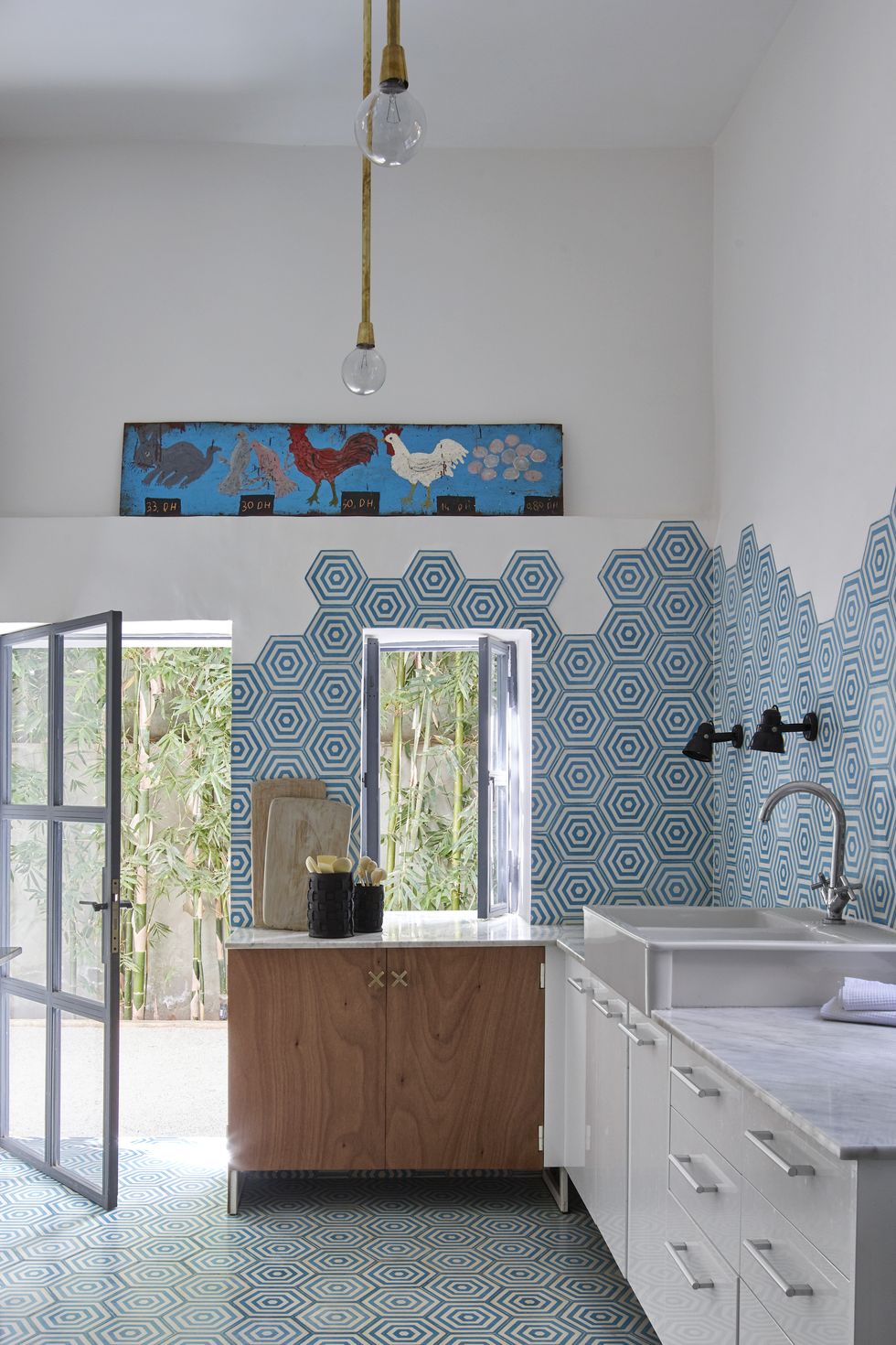 Phòng bếp ấn tượng nhờ sử dụng gạch ốp tường và lát sàn màu xanh lam với họa tiết tổ ong (hình lục giác) đẹp đến mê hồn. Mặt bàn bằng đá cẩm thạch Ma-rốc cùng tủ gỗ cho không gian ấm áp hơn.