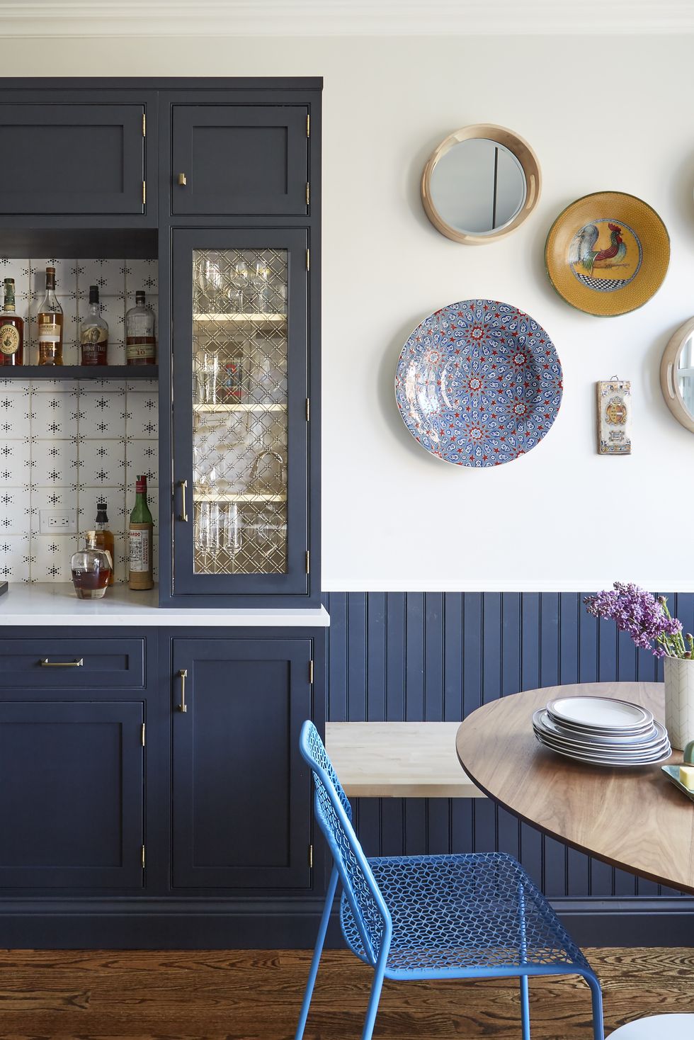 NTK nội thất đã lựa chọn tone màu xanh xám đậm cho tủ bếp và gỗ ốp tường, ghế ngồi màu xanh lam nhạt cùng những chi tiết như đĩa trang trí trên tường cho bếp nhỏ kết hợp khu vực ăn uống quyến rũ.