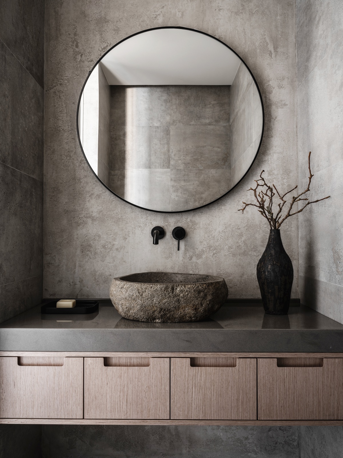 Một phòng tắm với gam màu xám lạnh nhưng vẫn khiến người nhìn mê đắm bởi nét đẹp chân thực của nội thất. Tủ lưu trữ gỗ, chậu rửa mặt đá tự nhiên kết hợp chiếc bình gốm vô cùng hài hòa và tinh tế.