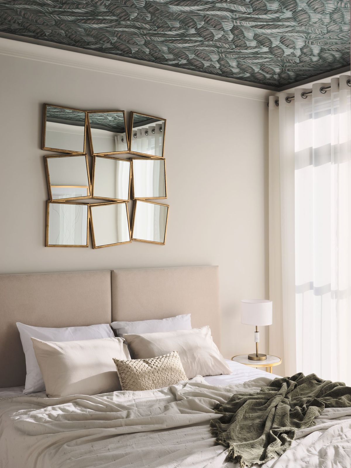 Không gian phòng ngủ sử dụng tone pastel dịu nhẹ cho nền tường và nội thất, kết hợp điểm nhấn là giấy dán tường tương phản trên trần nhà. Thêm vào một tấm gương lớn được kết hợp từ 9 tấm gương nhỏ hình vuông tôn thêm vẻ đẹp hiện đại.