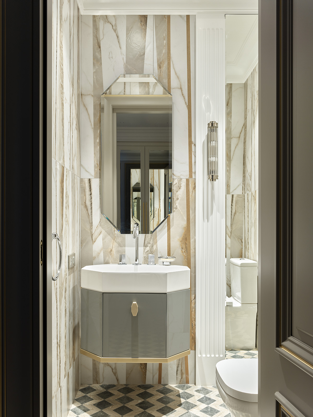 Khu vực rửa tay nằm trong góc phòng tắm được các NTK nội thất ưu ái lựa chọn gạch ốp tường là đá cẩm thạch đắt giá, thêm vào tấm gương hình bát giác tựa như một 'viên ngọc sáng' trên tường.