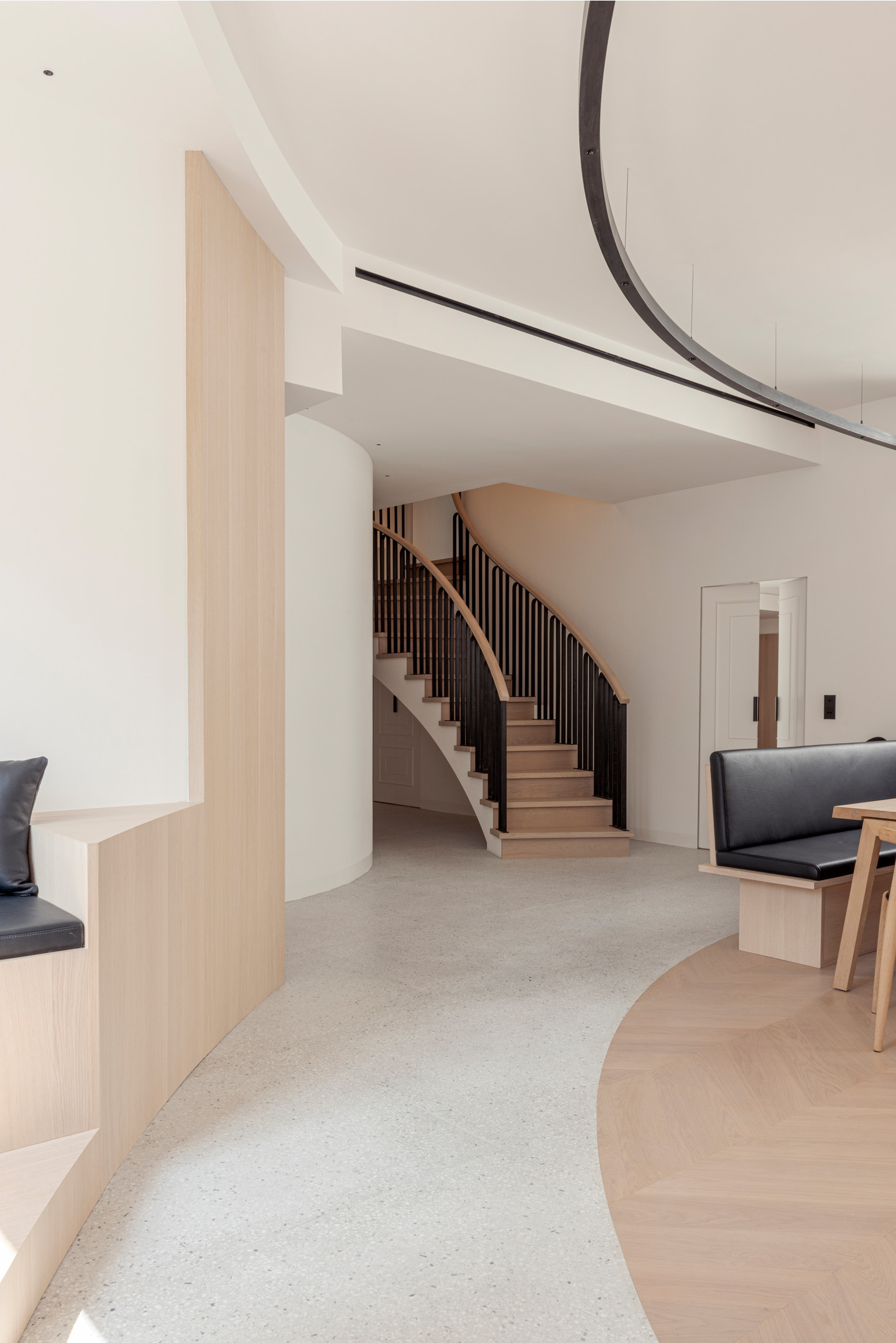 Cầu thang gỗ với lan can màu đen chuyển tiếp giữa 2 tầng được xem là điểm nhấn giữa không gian phủ đầy sắc màu trung tính. Tầng trên thiết kế gồm phòng sinh hoạt chung, phòng ngủ chính, phòng ngủ cho khách và phòng tắm.