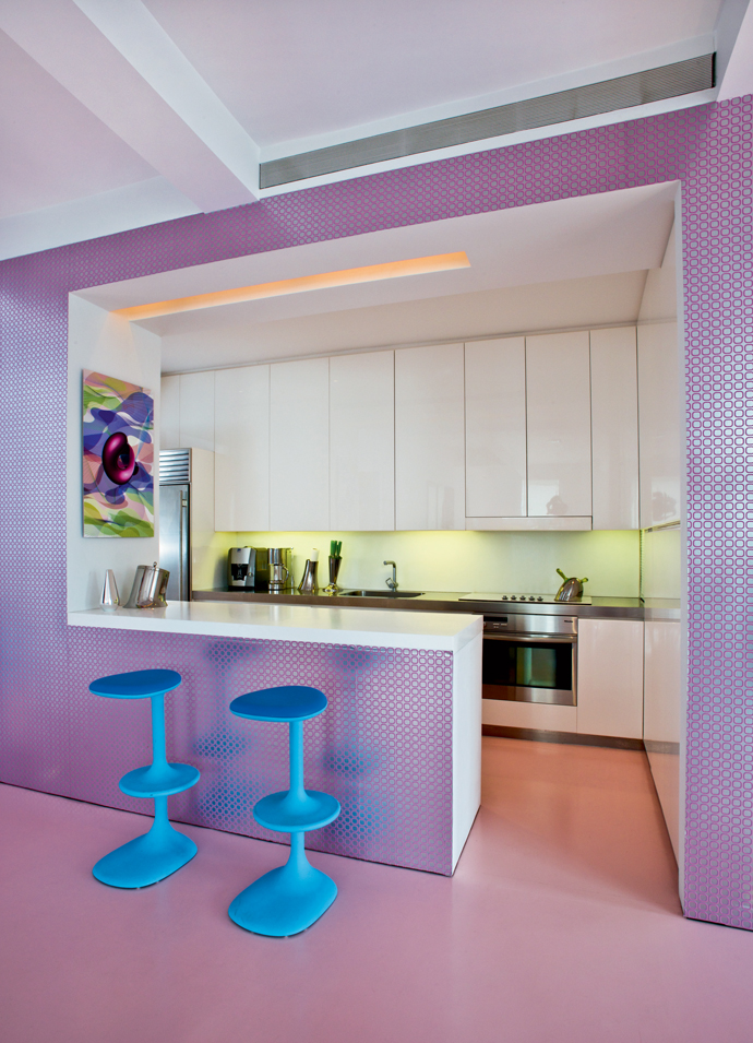 Không gian phòng bếp như được 'khoanh vùng', ngăn cách với các khu vực chức năng còn lại nhờ mẫu giấy dán giường màu tím neon lạ mắt, thêm vào cặp ghế đầu màu xanh lam nổi bần bật ở quầy bar nhỏ.