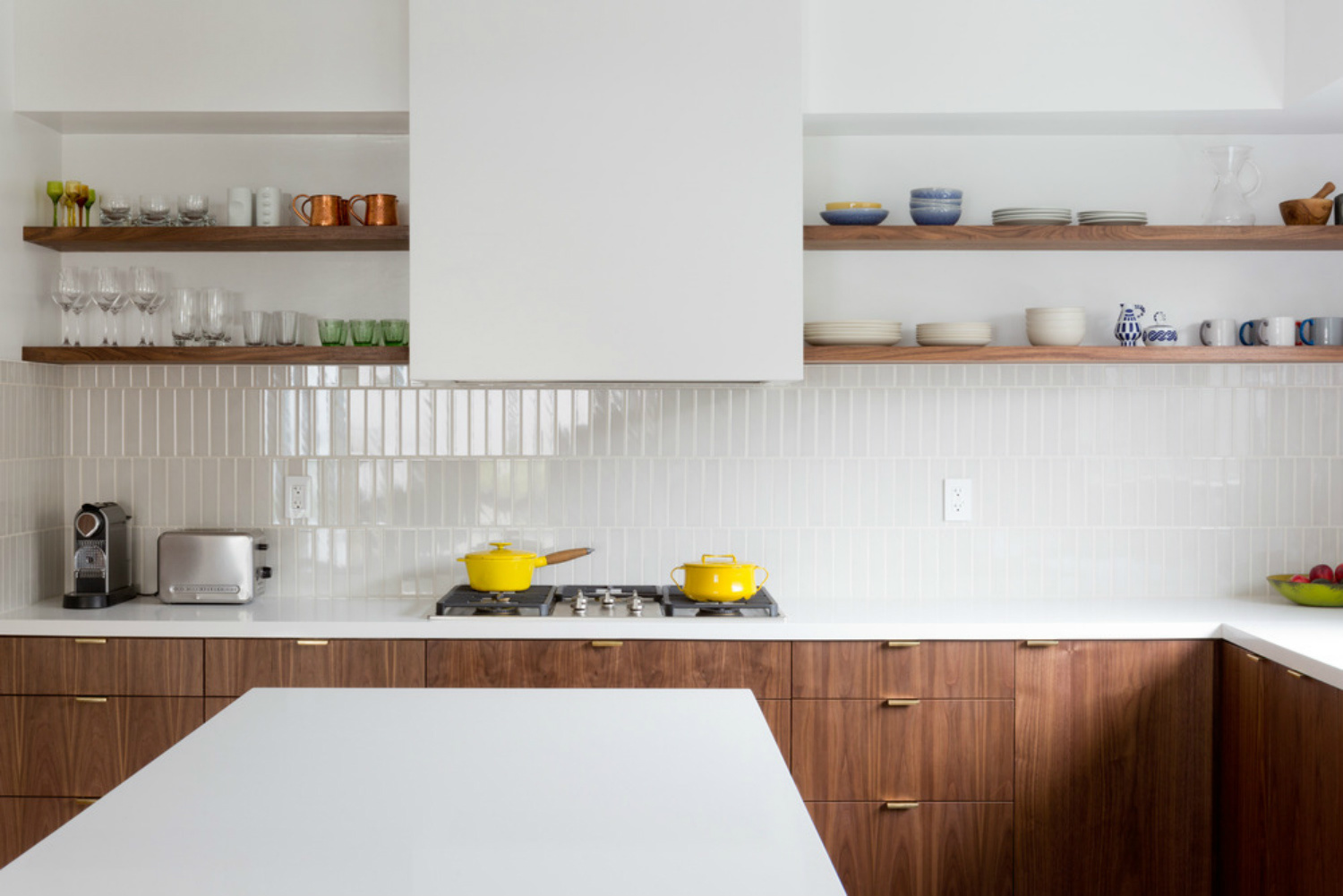Nếu yêu phong cách tối giản, bạn có thể học hỏi cách thiết kế của phòng bếp này khi sử dụng gạch ốp backsplash màu trắng hòa quyện với mặt bàn bếp và màu sơn tường. Sử dụng hệ thống kệ mở bằng gỗ để tăng không gian lưu trữ hiệu quả.