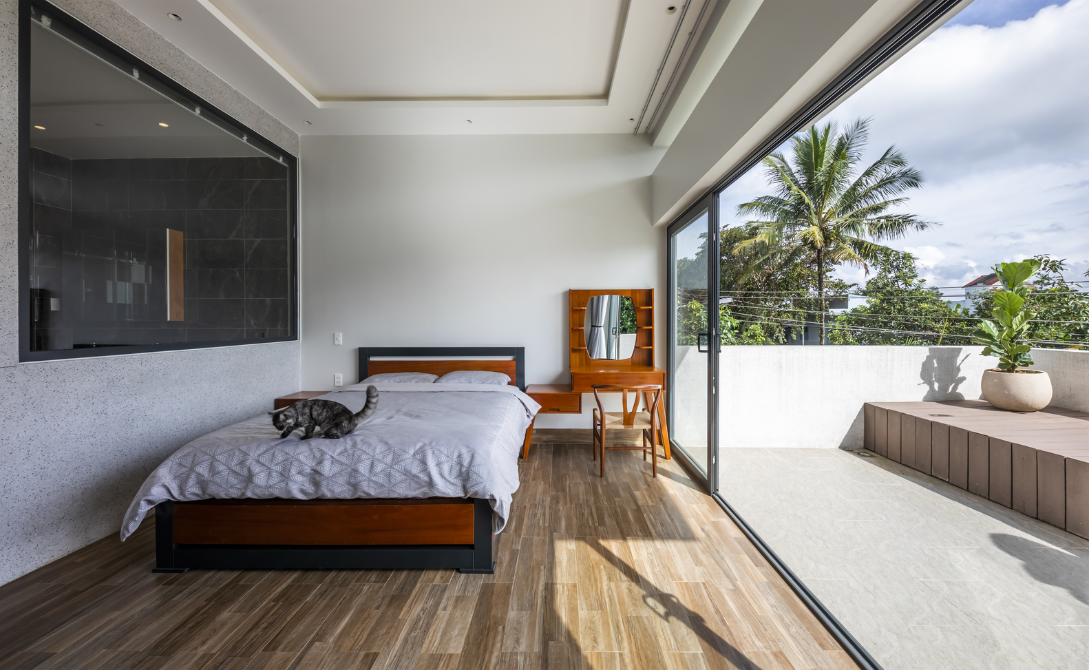 Phòng ngủ lát sàn gỗ ấm áp, kết nối với không gian ngoài trời bằng cửa kính trượt trong suốt, từ đây có thể phóng tầm mắt ngắm nhìn khung cảnh xanh mát của cao nguyên.