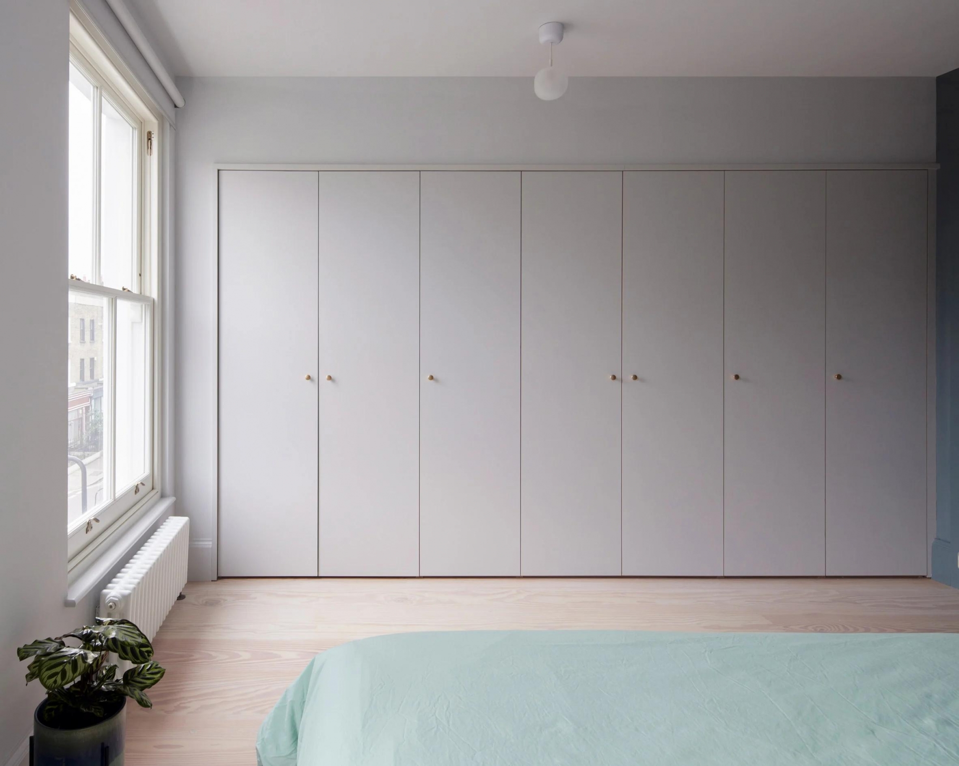 Một phòng ngủ khác sử dụng gam màu xám chủ đạo, kết hợp trần nhà trắng và sàn gỗ ấm áp. Tương tự phòng ngủ đầu tiên, việc tiết chế tối đa nội thất giúp căn phòng có nhiều không gian để 'thở' hơn.
