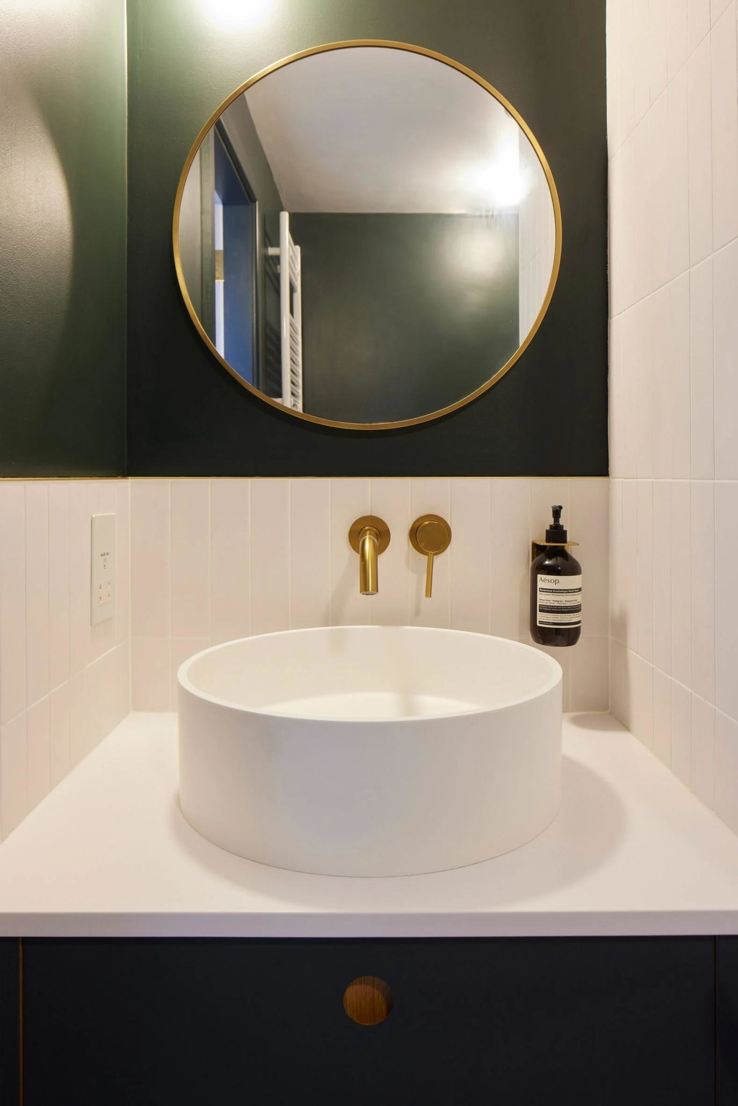 Và cuối cùng là không gian phòng tắm với điểm nhấn là bức tường sơn màu xanh rêu đậm, kết hợp những chi tiết bằng kim loại mạ vàng đồng như viền khung gương soi, vòi rửa tay,... nơi bồn rửa.