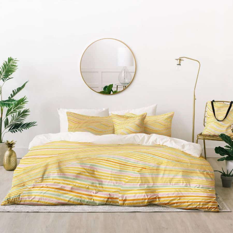 Phòng ngủ thiết kế tối giản bằng cách loại bỏ giường và thay bằng nệm dày cho cảm giác trần nhà cao thoáng hơn. Sắc vàng của bộ chăn ga gối kết hợp nhiều họa tiết màu pastel khác tôn lên vẻ trẻ trung cho không gian thư giãn.