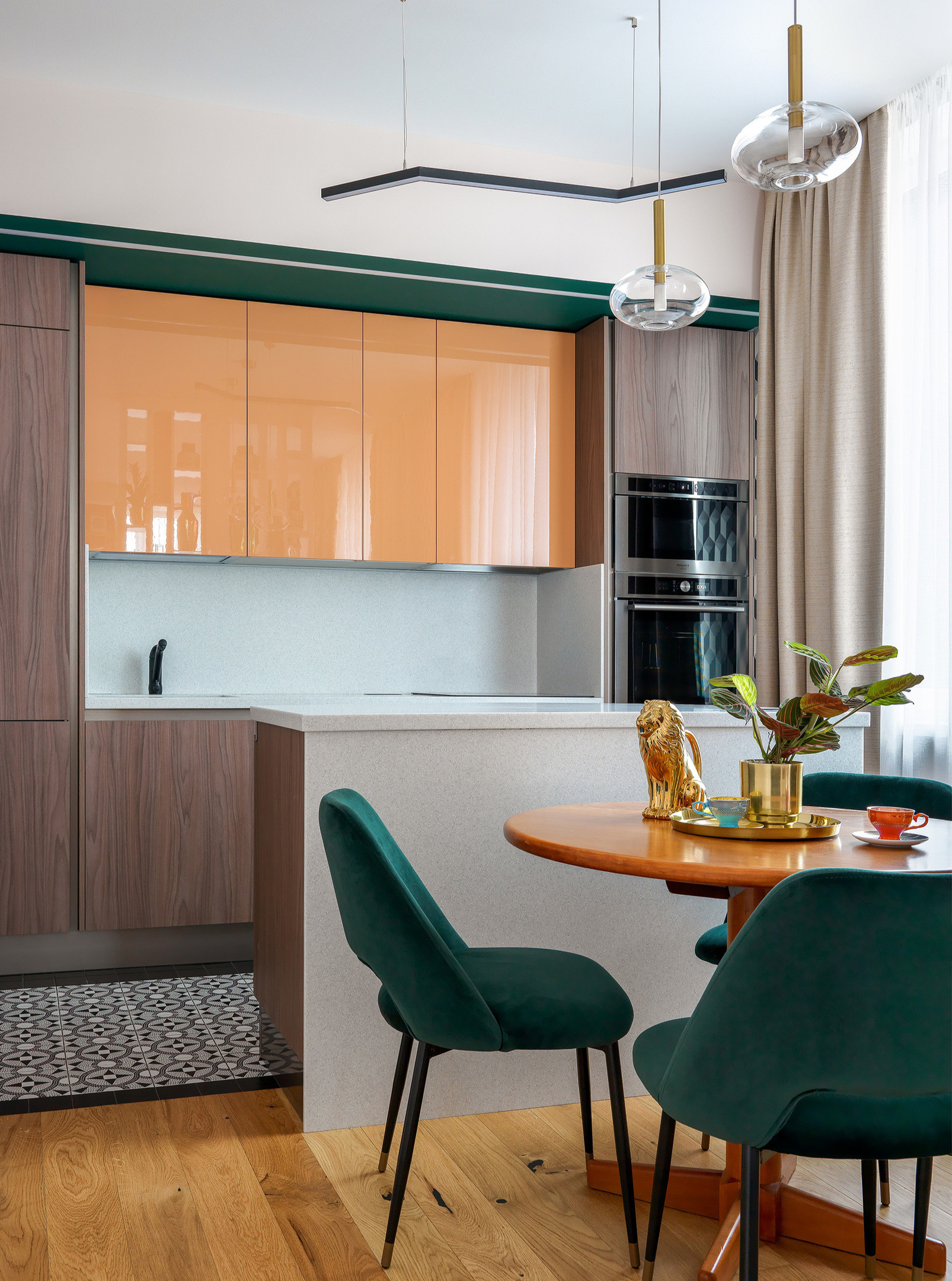 Màu sắc và vật liệu nội thất cũng là yếu tố quyết định đến tính thẩm mỹ của phòng bếp. Ở đây là sự kết hợp màu nâu gỗ, cam đào và xanh ngọc lục bảo, thêm vào bề mặt sáng bóng của hệ tủ bếp trên cho cảm giác tươi mới hơn.