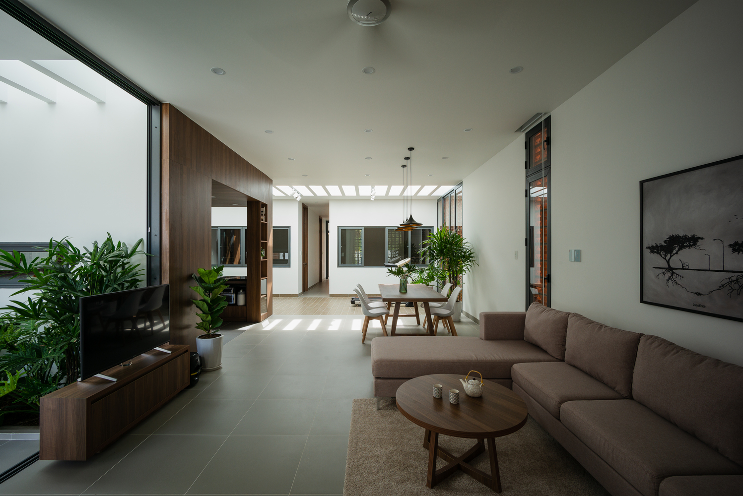 Không gian phòng khách nhẹ nhàng với tone trầm ấm của ghế sofa, bàn nước, kệ tivi bằng gỗ và thảm trải sàn ấm áp.