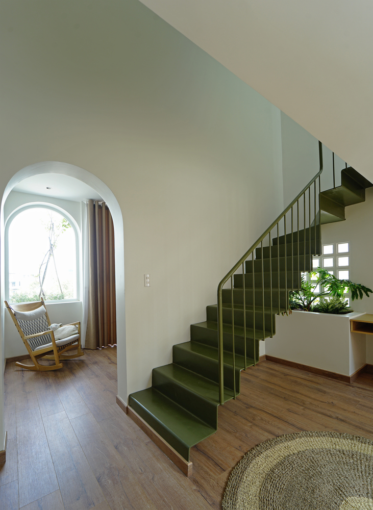 Cầu thang ở tầng tiếp theo với gam màu xanh rêu sang chảnh, tạo điểm nhấn nổi bật giữa tone màu trắng chủ đạo và sắc nâu ấm áp của gỗ. 