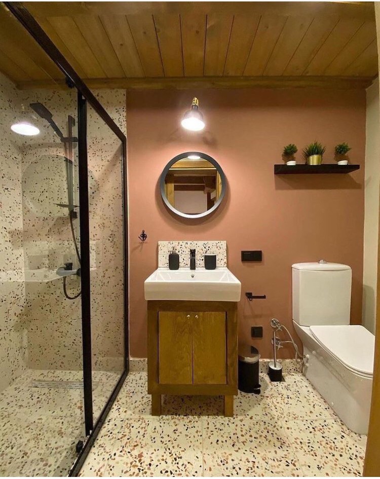 Nhà vệ sinh bố trí khoa học và đẹp mắt, khu vực tắm được ngăn cách bằng cửa kính. Tủ gỗ nhỏ bên dưới bệ rửa để cất giữ gọn đồ.
