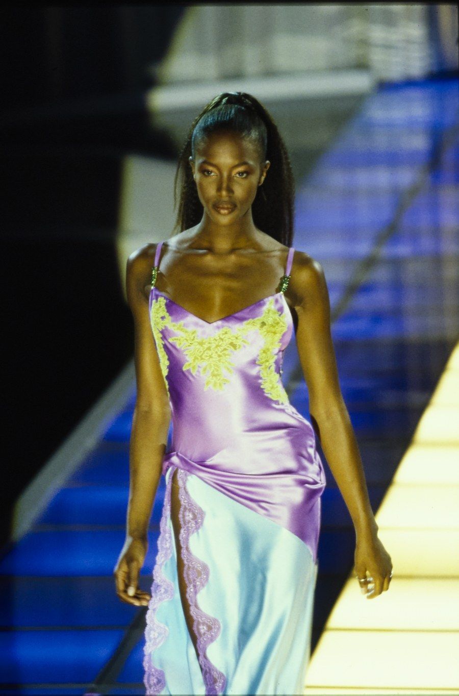Một thiết kế nổi bật khác phải kể đến là mẫu váy hai dây của Versace ra mắt lần đầu khi Naomi Campbell trình diễn trong show năm 1996. Vẻ đẹp duyên dáng của Naomi trong thiết kế tone xanh tím đáp ren đã để lại ấn tượng sâu đậm trong lòng khán giả. 