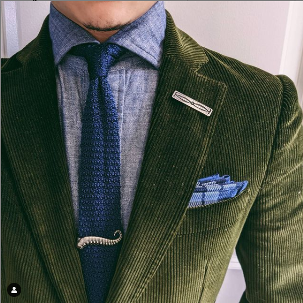 Áo vest nhung kết hợp cùng sơ mi và cà vạt xanh, tạo điểm nhấn cùng tie bar. Anh chàng sở hữu một bộ sưu tập ghim cài áo vô cùng đa dạng.